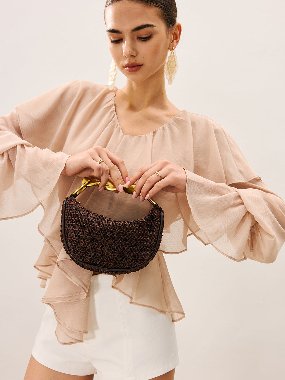 Handtasche aus gewebtem Material mit verdrehtem goldenem Henkel